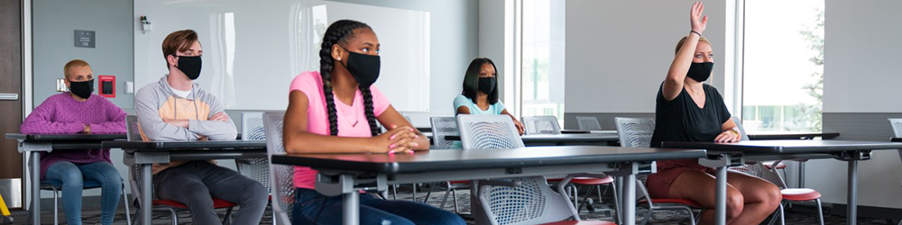 Students sit in a classroom wearing masks and socially distanced