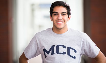 Student smiles at camera in grey MCC t-shirt
