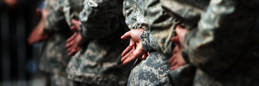 Military service members in uniform with their hands out ready to receive their degrees and certificates from MCC